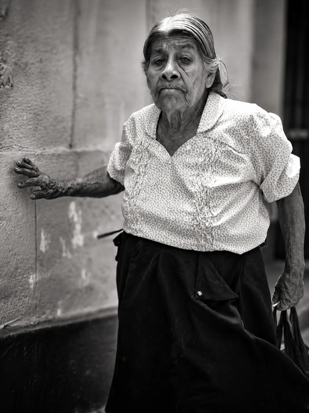 Mujer mayor de pie retratada en blanco y negro
