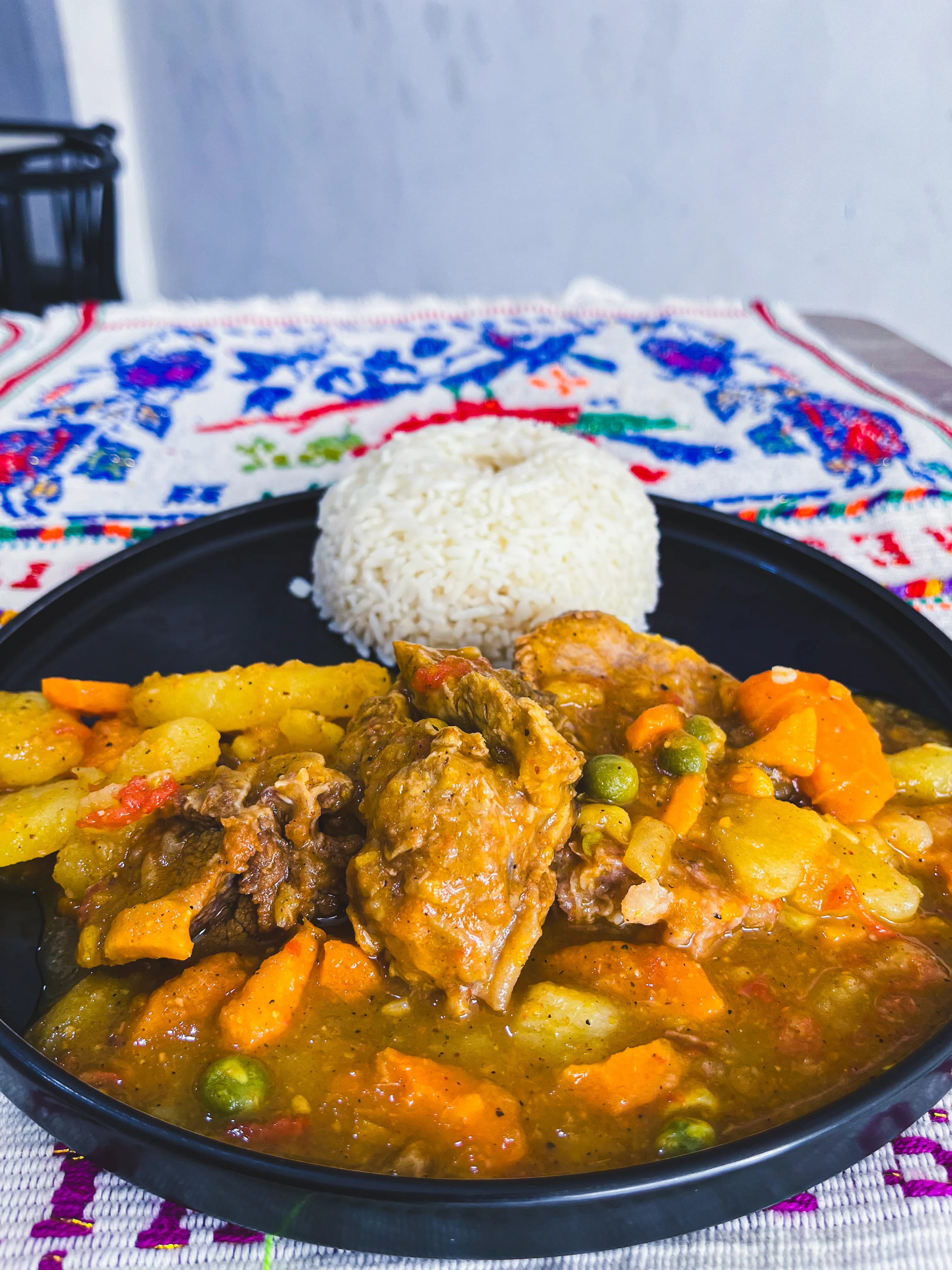 Plato hondo con pato guisado, vegetales y una porción de arroz blanco